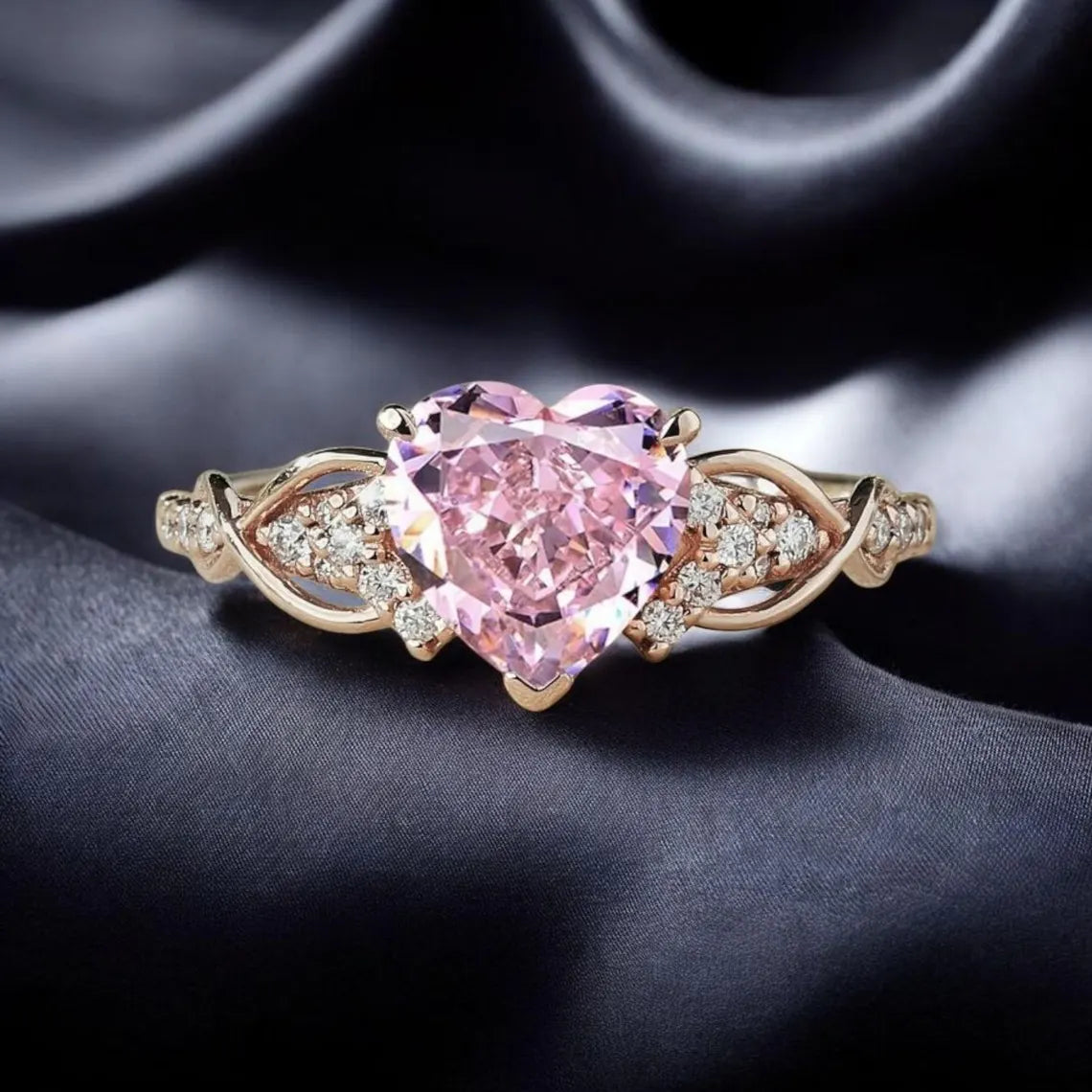 Rose gold ring with a heart-shaped pink gemstone on a dark fabric background
