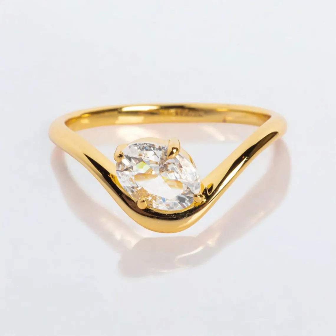 Gold ring with a clear gemstone on a light gray background